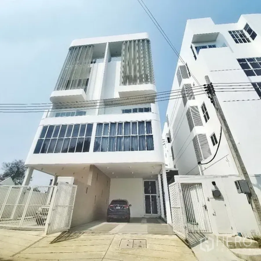 Home Office for rent or sale in Prawet, Bangkok - Five-storey modern white home office exterior with vertical fins, gated driveway and carport in Prawet, Bangkok.