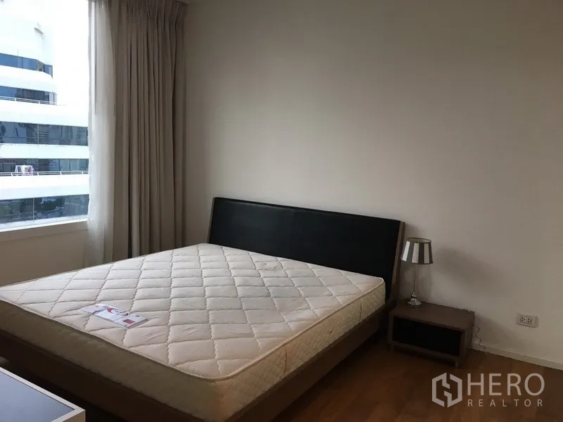 Condominium for rent in Watthana, Bangkok - Bedroom with large window, queen bed and bedside table.