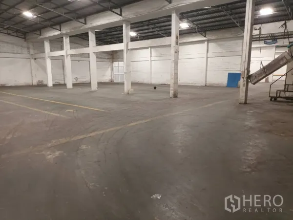 Warehouse for rent in Bang Phli, Samut Prakan - Wide warehouse interior with high ceiling, concrete floor and white support columns.