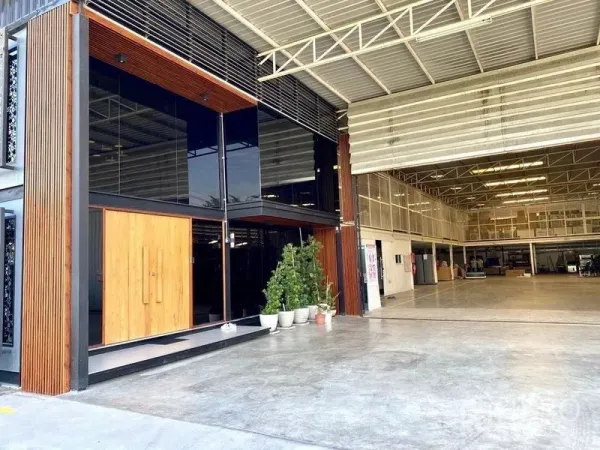 Warehouse for sale in Min Buri, Bangkok - Warehouse facade with glass-front office, wood accents and a large roller shutter entrance.