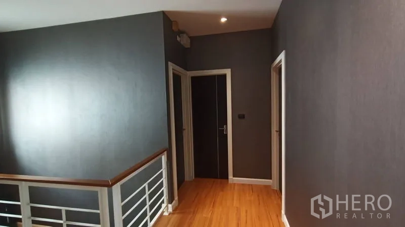 独立式住宅 出售在Prawet, Bangkok - 走廊与楼梯平台，木地板和白色室内门。