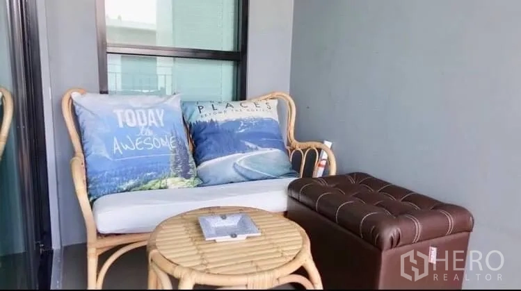 ทาวน์เฮาส์ ให้เช่าหรือขายในSuan Luang, Bangkok - ระเบียงกะทัดรัด พร้อมโซฟาหวายและสตูลหนัง โต๊ะกลมเล็ก