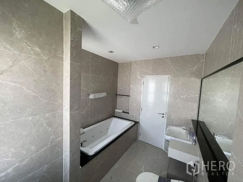 独立式住宅 出售在Bueng Kum, Bangkok - 主卫配按摩浴缸、超长镜面与石纹瓷砖。