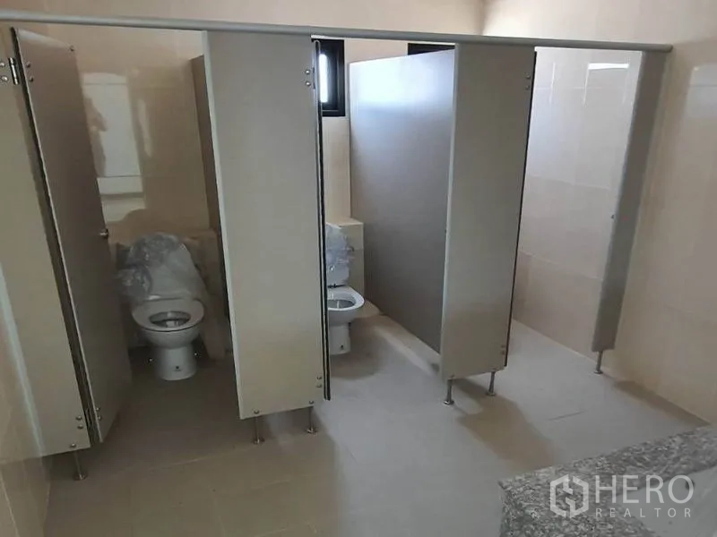 Warehouse for rent in Samut Prakan - Clean staff restroom with multiple toilet cubicles in light finishes.