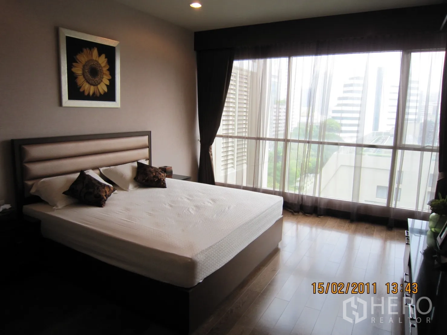 คอนโด ให้เช่าหรือขายในPathum Wan, Bangkok - ห้องนอนสว่าง เตียงคิงไซส์ หน้าต่างแบบเต็มผนัง ผ้าม่านโปร่ง พื้นไม้ และวิวเมือง