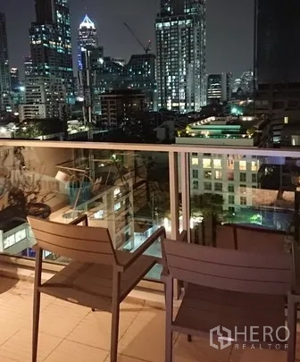 คอนโด ให้เช่าในPathum Wan, Bangkok - ระเบียงส่วนตัวพร้อมเก้าอี้สองตัว มองเห็นวิวสกายไลน์กรุงเทพฯ ยามค่ำคืน