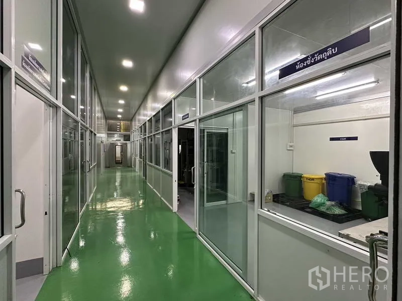 Factory for rent in Khlong Luang, Pathum Thani - Clean production corridor with glass-partitioned rooms, bright LED lighting and green epoxy floor.