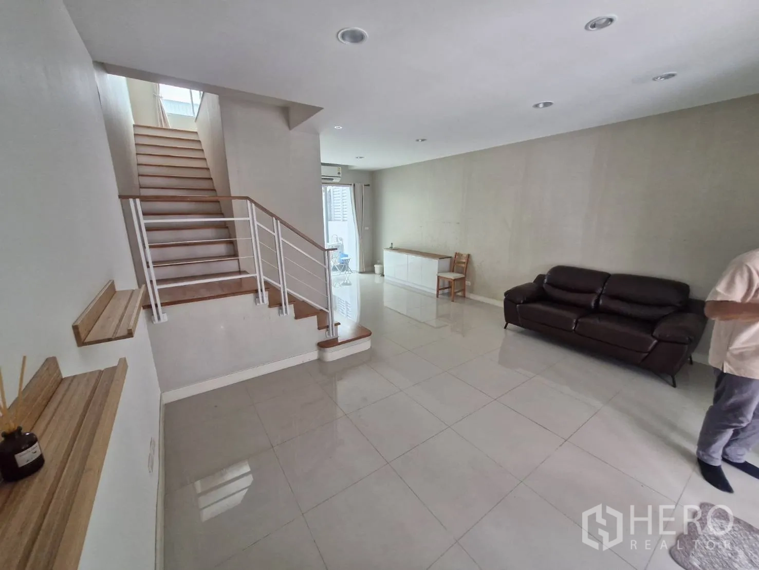 Townhouse for sale in Rat Burana, Bangkok - Open-plan living room with staircase, glossy tiles, and sofa.