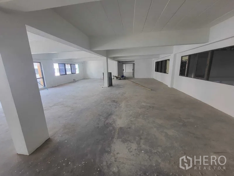 Factory for rent or sale in Samut Prakan - Bright office level with multiple windows and unfinished flooring.