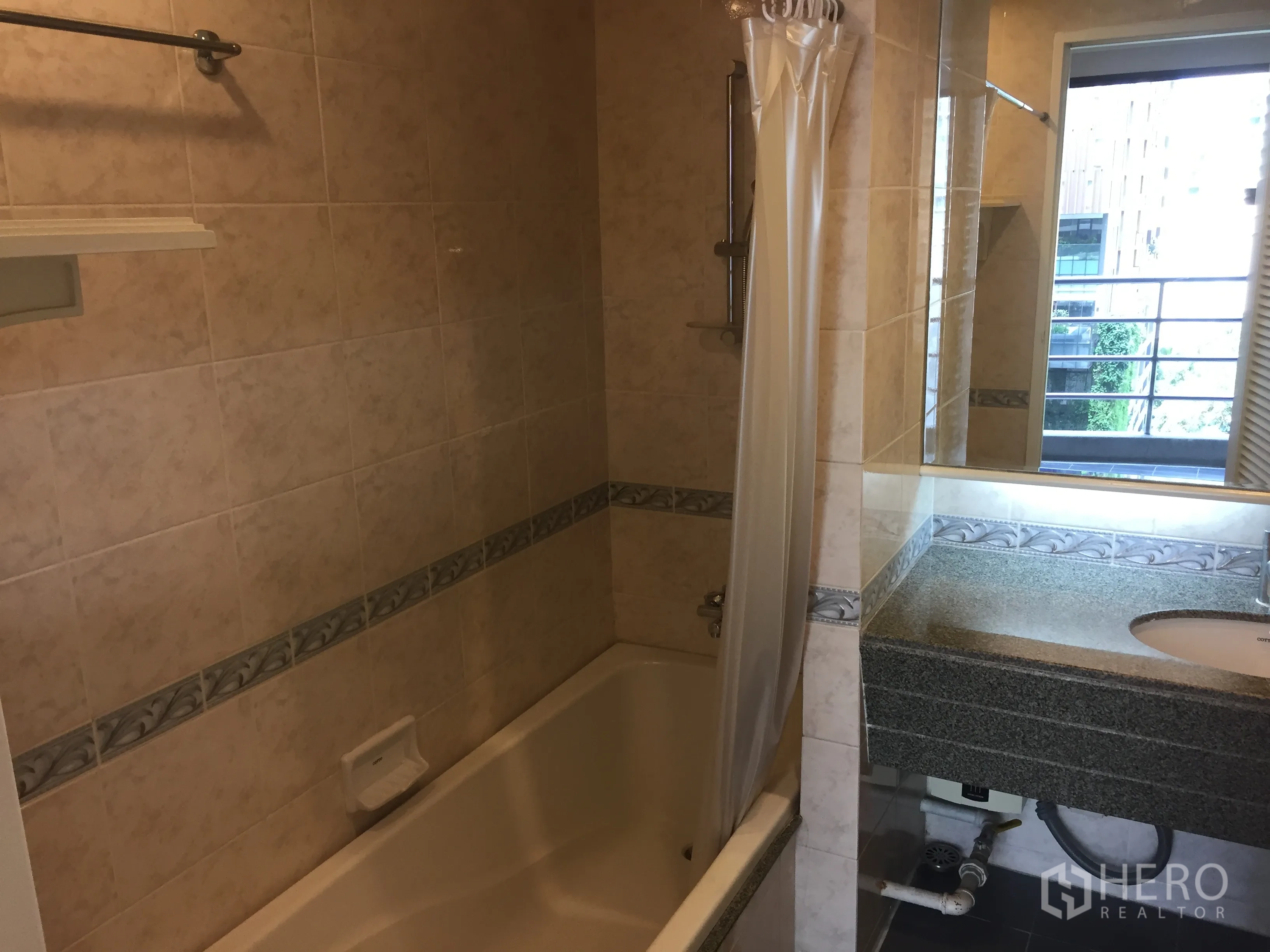 Condominium for rent in Pathum Wan, Bangkok - Tiled bathroom with bathtub, granite vanity, large mirror and window.