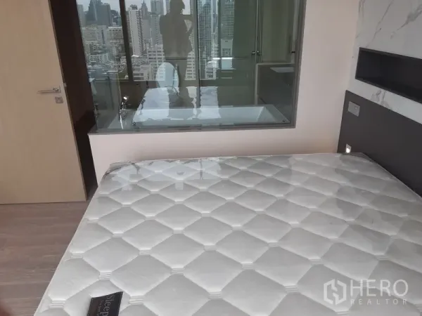 คอนโด ให้เช่าหรือขายในWatthana, Bangkok - มุมห้องนอนมองไปยังห้องน้ำกั้นกระจกพร้อมฉากหลังเป็นวิวเมือง