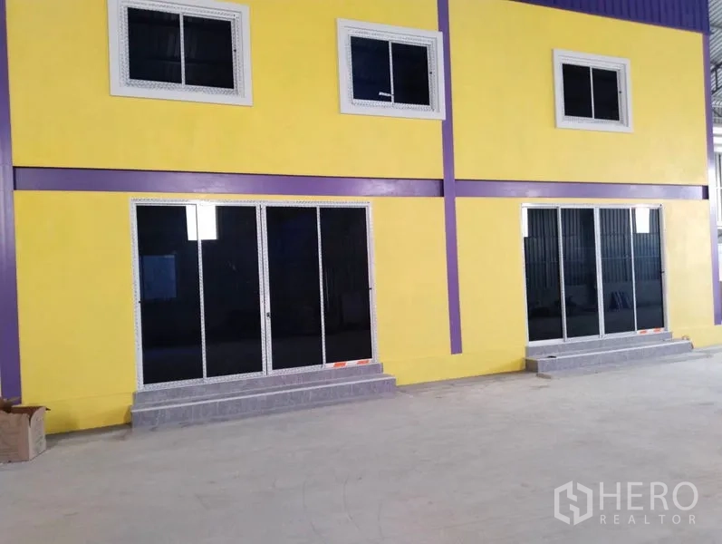 Warehouse for sale in Sai Noi, Nonthaburi - Close-up of the two-storey yellow office with sliding glass doors and windows inside the warehouse.