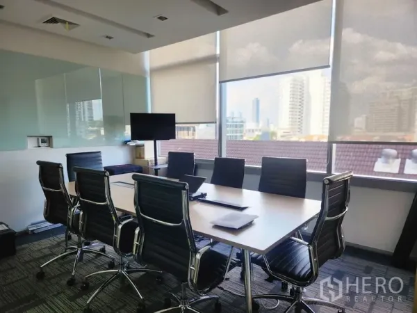 Office Space for rent in Watthana, Bangkok - Sunlit meeting room with eight leather chairs, large table, TV screen and city views through wide windows with roller blinds.