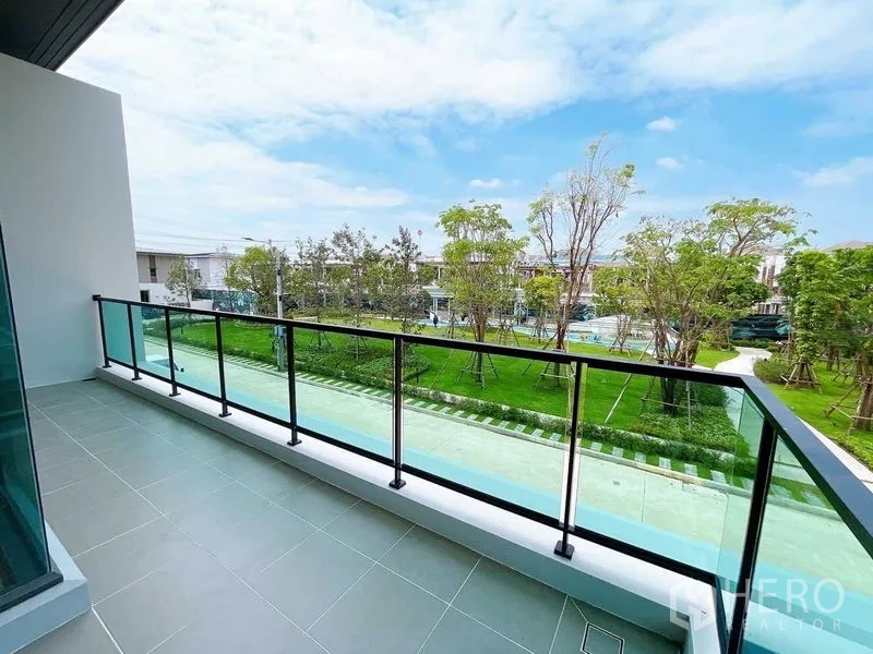 Detached House for sale in Don Mueang, Bangkok - Spacious upper balcony with glass railing facing green communal gardens.