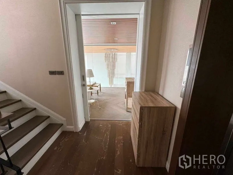 ทาวน์เฮาส์ ให้เช่าในWatthana, Bangkok - โถงทางเดินติดบันไดเปิดสู่มุมนั่งเล่น พื้นไม้และโคมแขวนตกแต่ง.