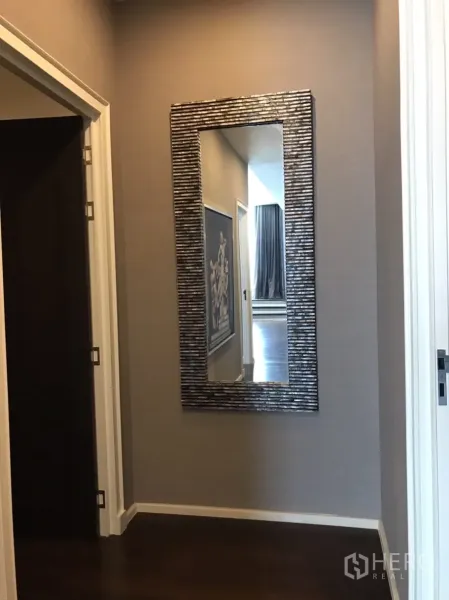 Condominium for rent or sale in Huai Khwang, Bangkok - Hallway with dark wood floors and a decorative full-length wall mirror.