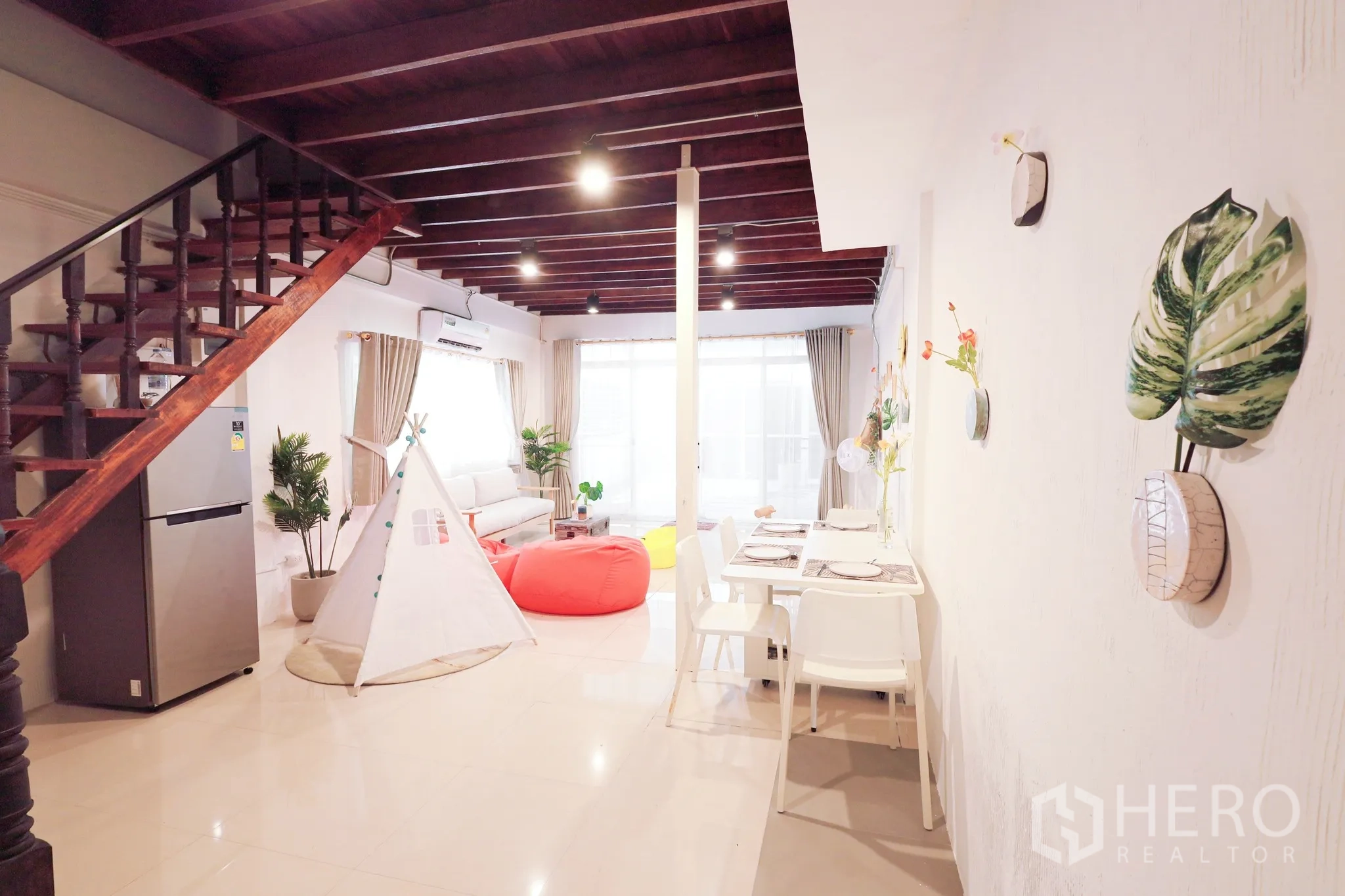 Townhouse for rent in Din Daeng, Bangkok - Bright open-plan living and dining area with exposed wooden beams, staircase, beanbags and a small teepee tent.