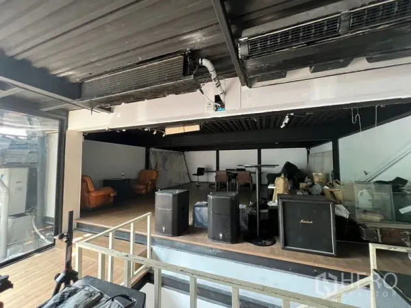 零售空间 出租 - 工业风抬高区，摆放音箱与皮质沙发，侧墙为玻璃