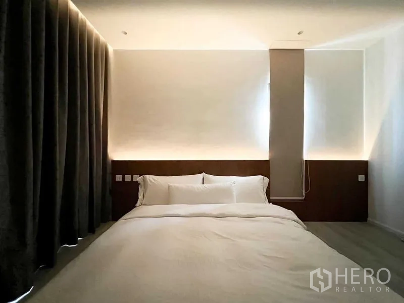 Condominium for rent or sale - Bedroom at night with blackout curtains and ambient cove lighting behind the headboard.