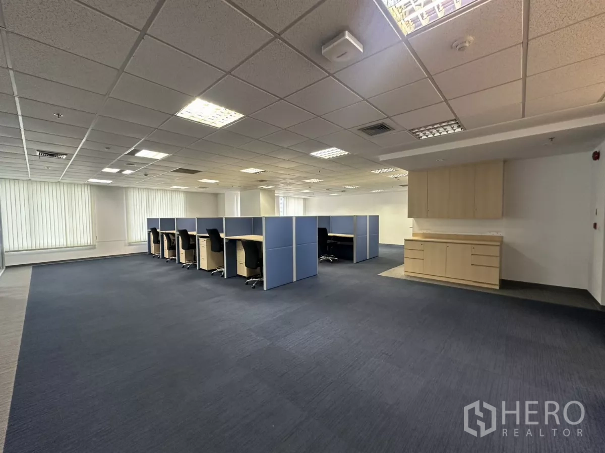 Office Space for rent in Watthana, Bangkok - Open-plan workspace with blue cubicles, carpet flooring, built-in storage and a pantry cabinet.