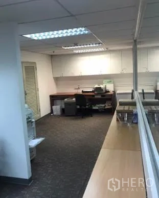 办公空间 出租在Khlong Toei, Bangkok - 打印与茶水区，内置白色柜体、办公桌与地毯地面，旁为玻璃隔断。