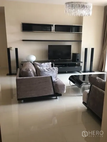 公寓 出租在Bang Rak, Bangkok - 现代客厅，灰色沙发、玻璃茶几、电视柜与水晶吊灯。