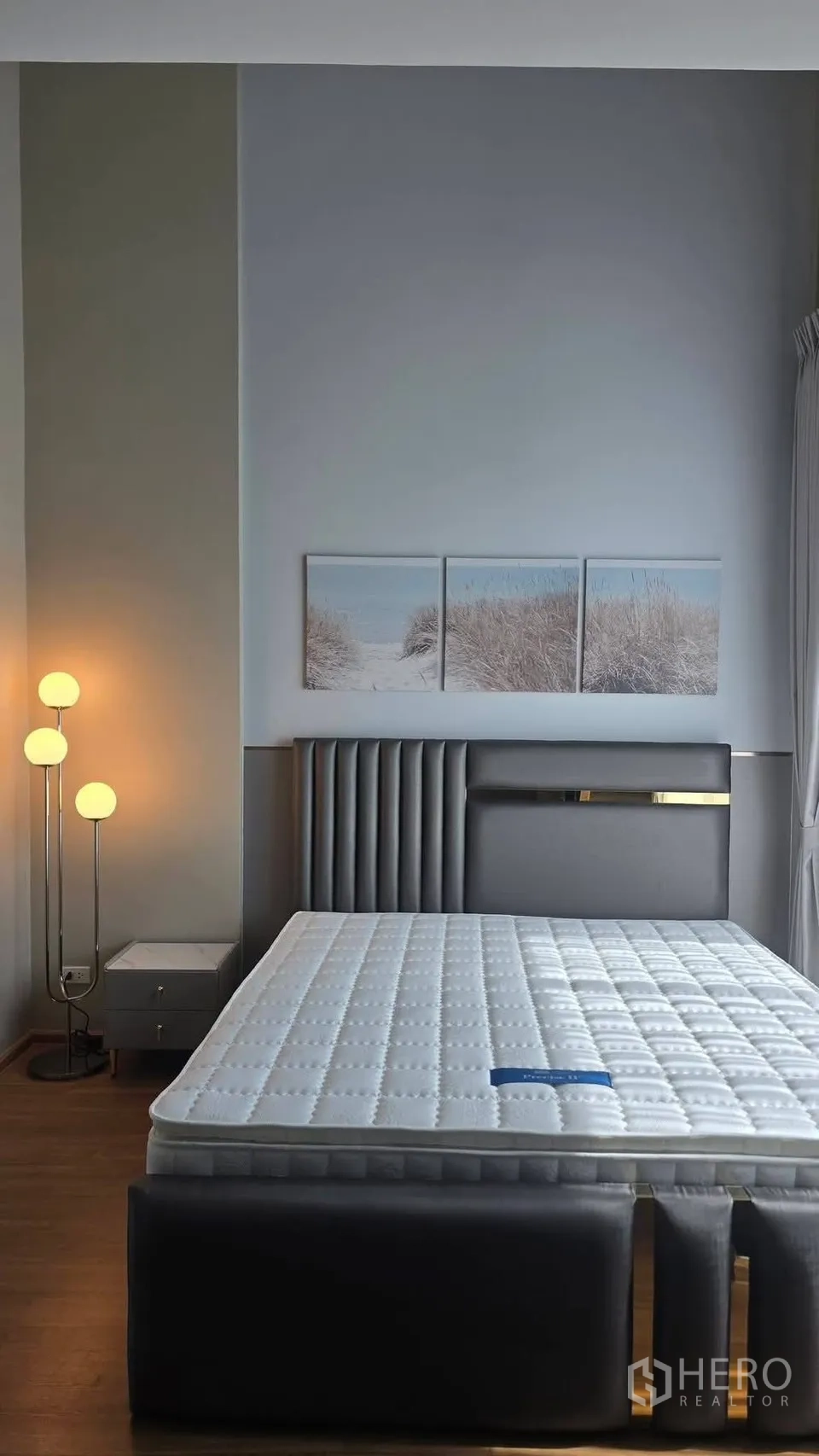 Townhouse for rent in Bang Phli, Samut Prakan - Master bedroom with tall upholstered headboard, floor lamp, and artwork.