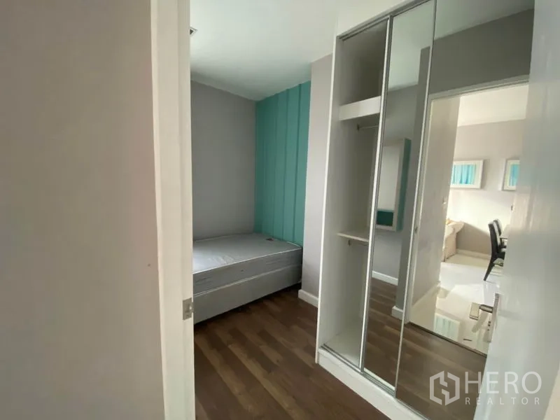Condominium for rent in Watthana, Bangkok - Second bedroom with teal accent wall, built-in mirrored wardrobe and wood floor