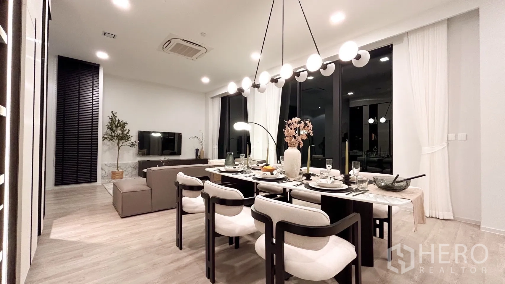 独立式住宅 出租在Saphan Sung, Bangkok - 夜景餐厅与客厅，落地窗与线性吊灯。