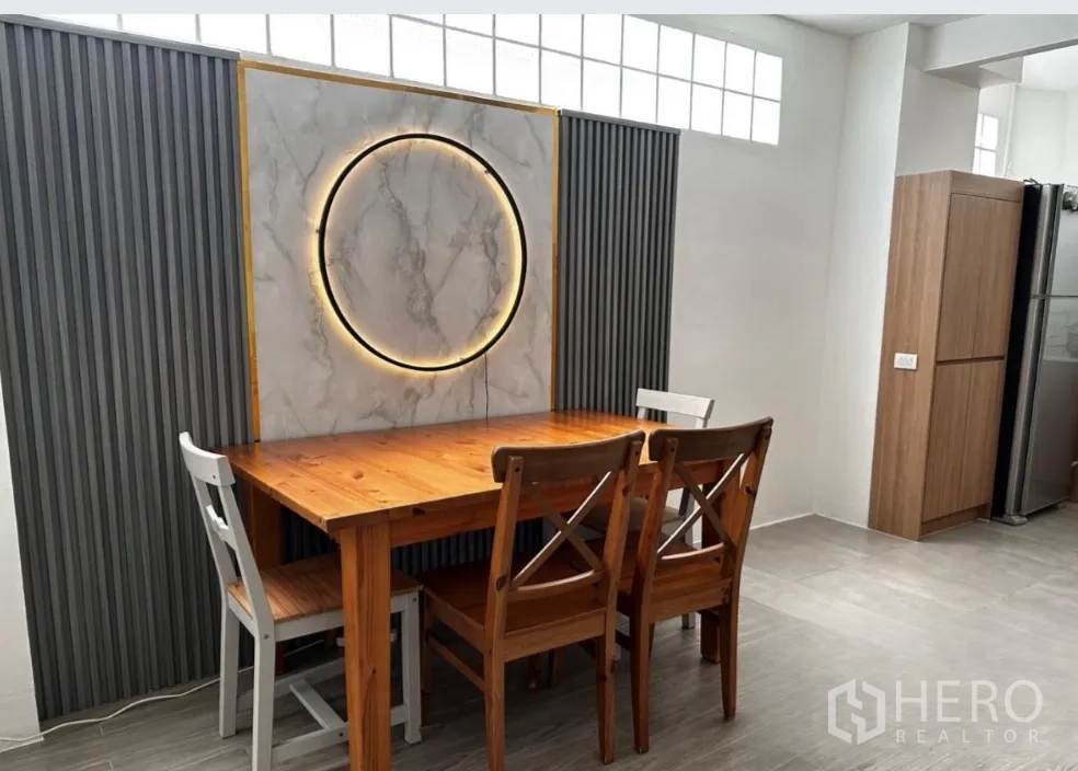 Townhouse for rent in Sathon, Bangkok - Dining area with wooden table, mixed chairs, and decorative wall lighting.