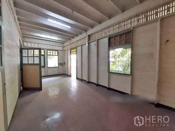 Detached House for rent in Bang Rak, Bangkok - Long open room with wood floors, white paneled walls, and multiple windows.