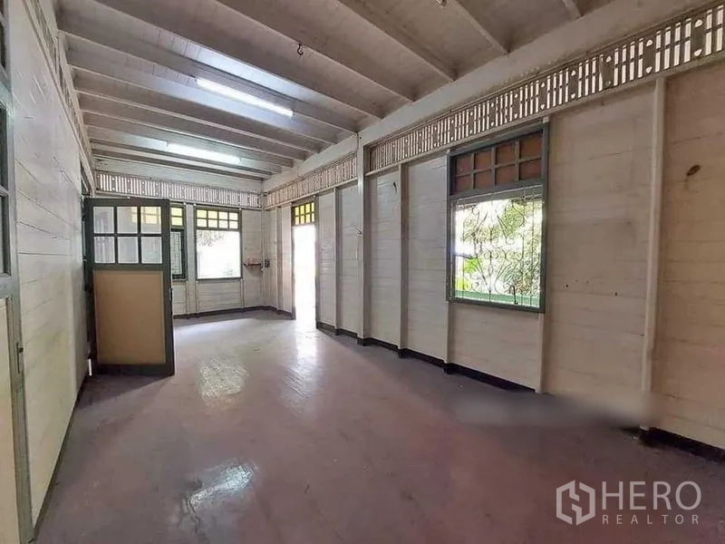 Detached House for rent in Bang Rak, Bangkok - Long open room with wood floors, white paneled walls, and multiple windows.