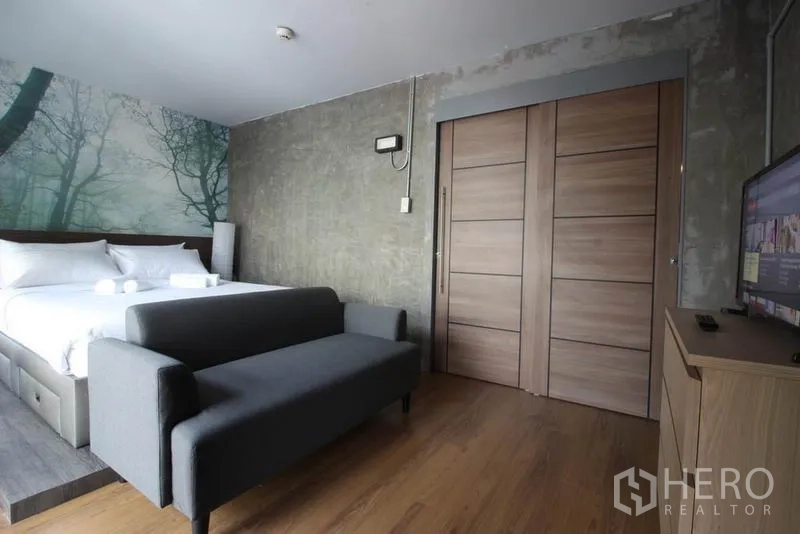 办公空间 出租或出售在Bang Rak, Bangkok - 套房视角，灰色沙发、木质推拉门与电视柜。