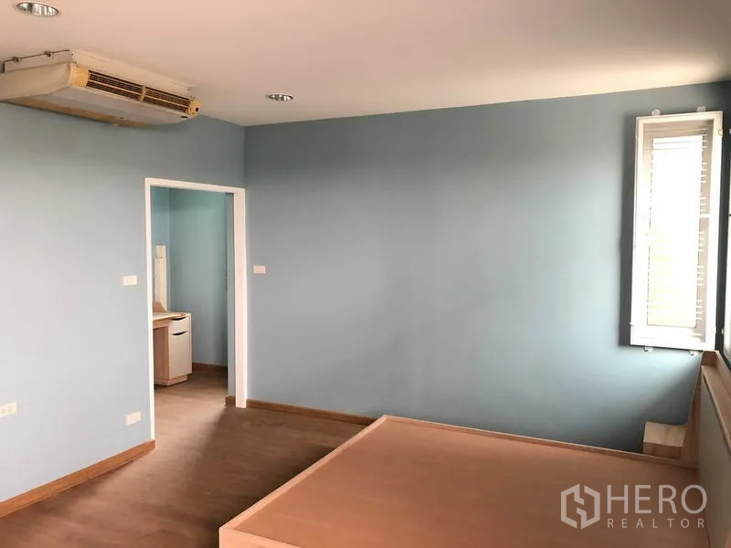 独立式住宅 出售在Bang Khen, Bangkok - 卧室带平台床、蓝色墙面、转角窗以及通向更衣或卫浴的门。