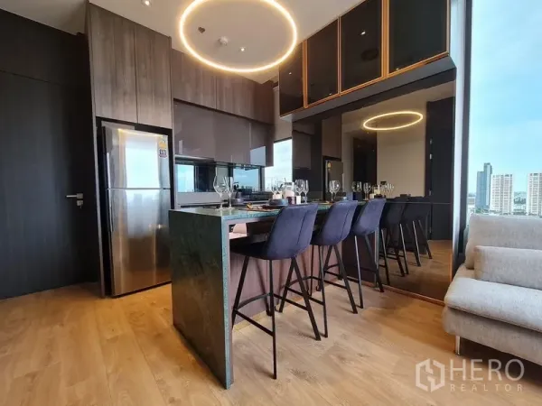 Condominium for rent - Modern kitchen with island breakfast bar, wood cabinetry and circular pendant light.