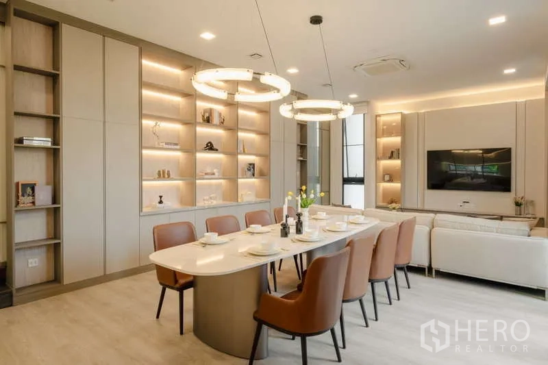 Detached House for rent in Saphan Sung, Bangkok - Open-plan dining and living room with illuminated built-in shelves and ring chandeliers.