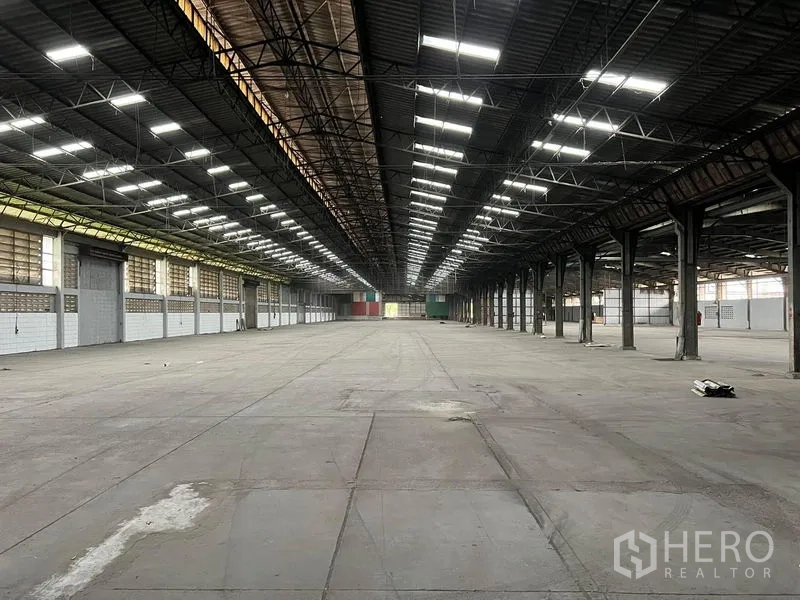 货栈 出租在Bang Pa-in, Phra Nakhon Si Ayutthaya - 仓库中央通道，屋顶灯带对称，尽头有集装箱