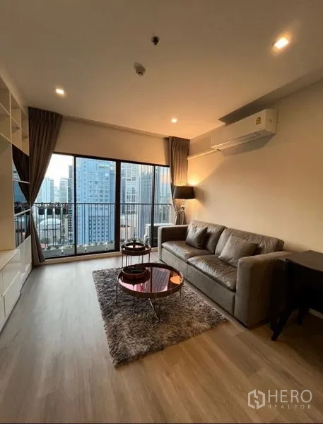 คอนโด ให้เช่าในBangkok - ห้องนั่งเล่นคอนโดสว่าง พร้อมโซฟา โต๊ะกลม และระเบียงวิวเมืองย่านคลองเตย กรุงเทพฯ