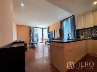 คอนโด ขาย - ครัวแบบเปิดท็อปสีดำและผนังกระเบื้อง เชื่อมต่อสู่พื้นที่นั่งเล่นและระเบียง