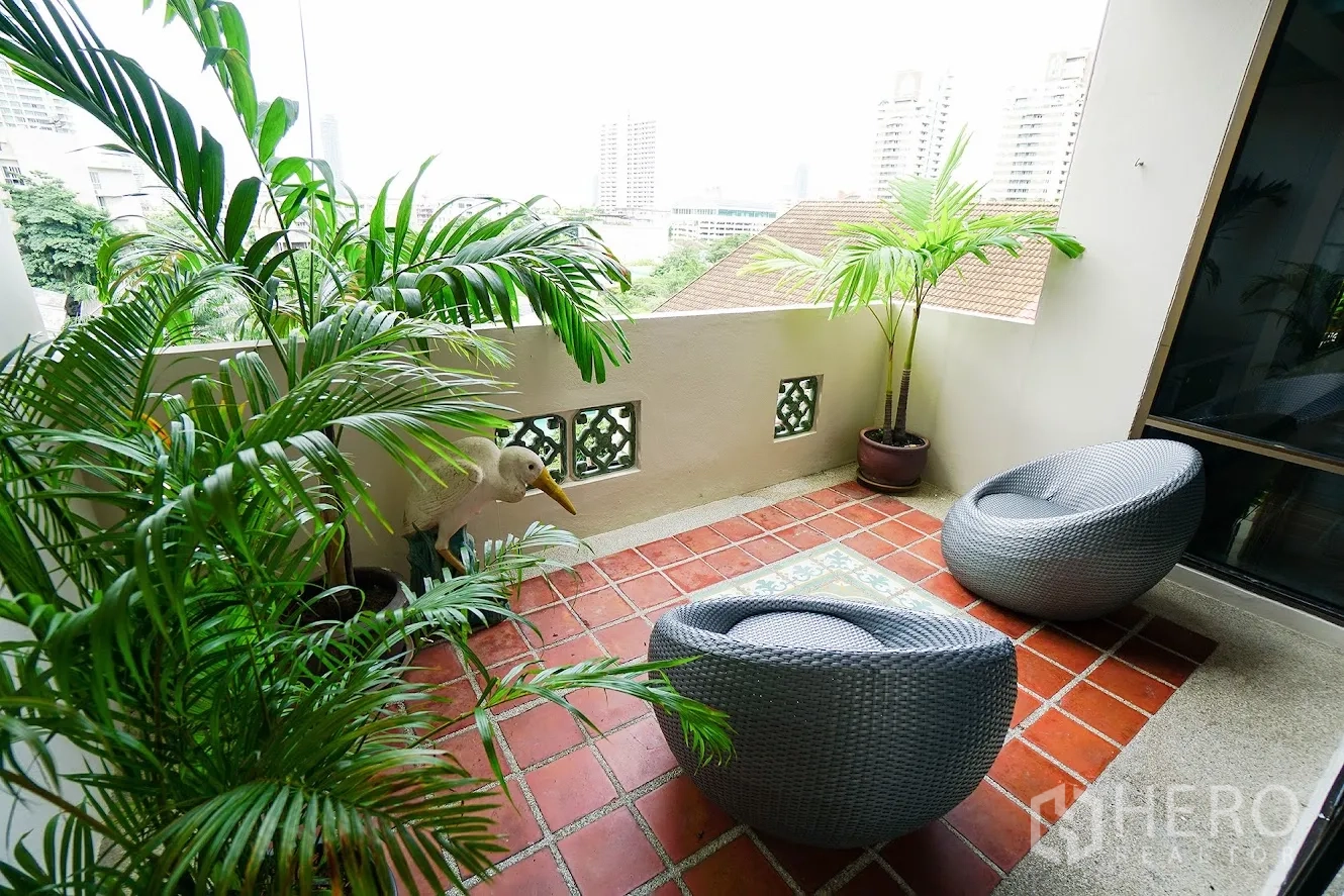 房间 出租在Watthana, Bangkok - 温馨露台，赤陶地砖、藤编休闲椅与盆栽棕榈。