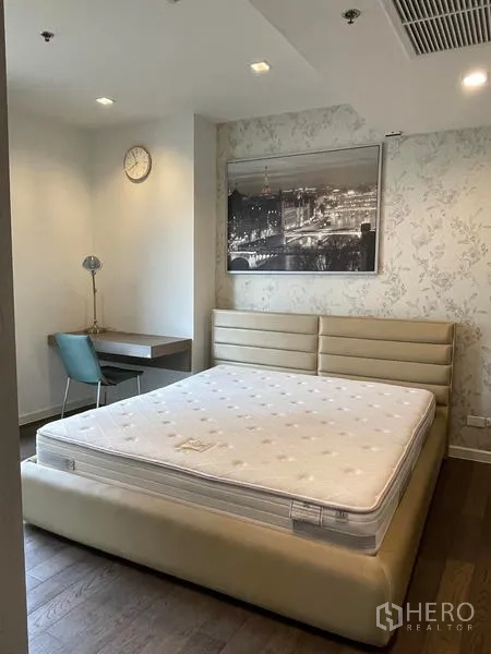 Condominium for rent in Sathon, Bangkok - Spacious master bedroom with upholstered bed frame, desk corner and patterned wallpaper.