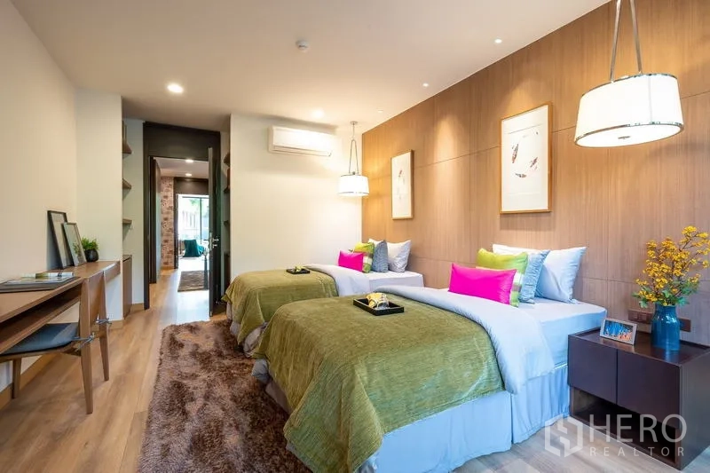 Condominium for sale - Spacious twin bedroom with wood wall paneling, study desk and soft pendant lighting.