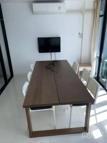 Office Space for sale in Saphan Sung, Bangkok - Bright meeting room with a long wooden table, white chairs, wall-mounted TV and air conditioner.