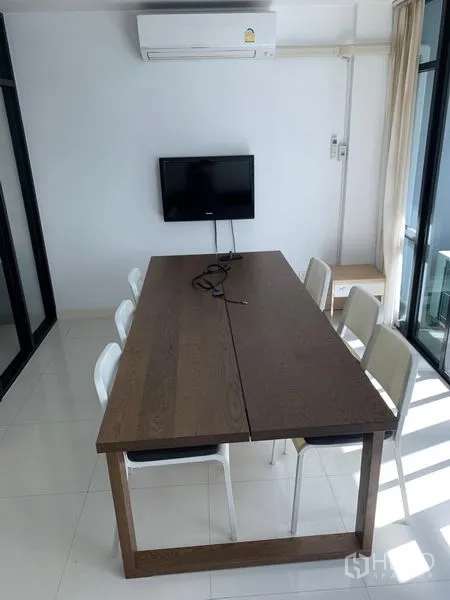 Office Space for sale in Saphan Sung, Bangkok - Bright meeting room with a long wooden table, white chairs, wall-mounted TV and air conditioner.