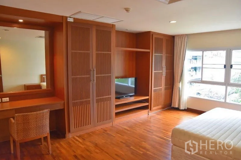 房间 出租在Sathon, Bangkok - 主卧配木质衣柜、梳妆台和大窗户。