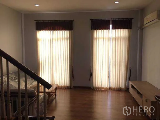 Home Office for rent in Wang Thonglang, Bangkok - Upstairs lounge with wood floors, tall curtained windows, air-conditioning and stair rail in a Bangkok home office.