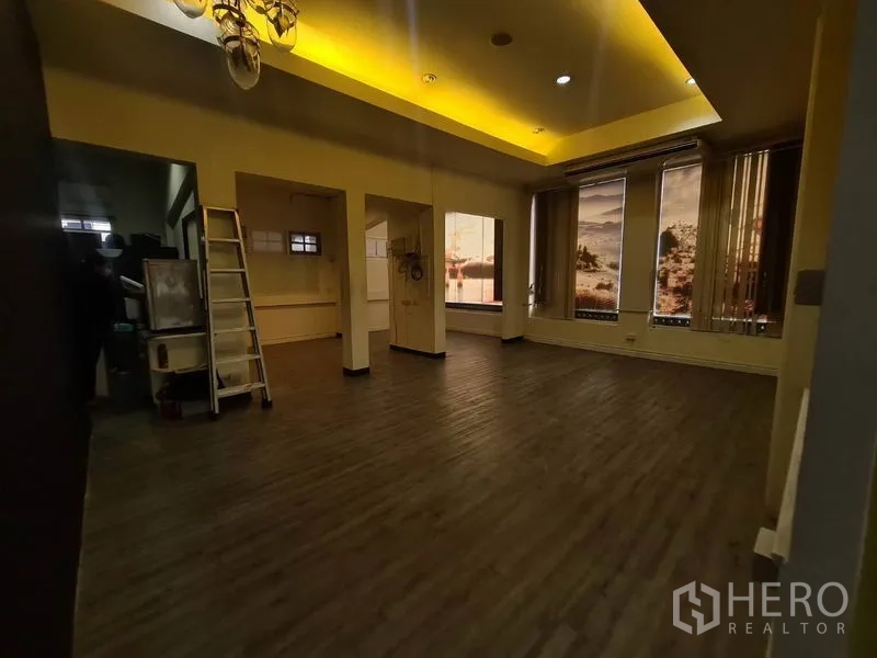 零售空间 出租在Watthana, Bangkok - 大空间，多扇高窗、灯槽天花与深色地板。