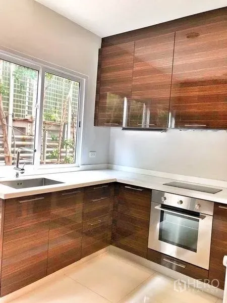 ทาวน์เฮาส์ ให้เช่าในWatthana, Bangkok - ครัวสไตล์ตะวันตกรูปตัวแอล ตู้ไม้ เตาอบ และหน้าต่าง