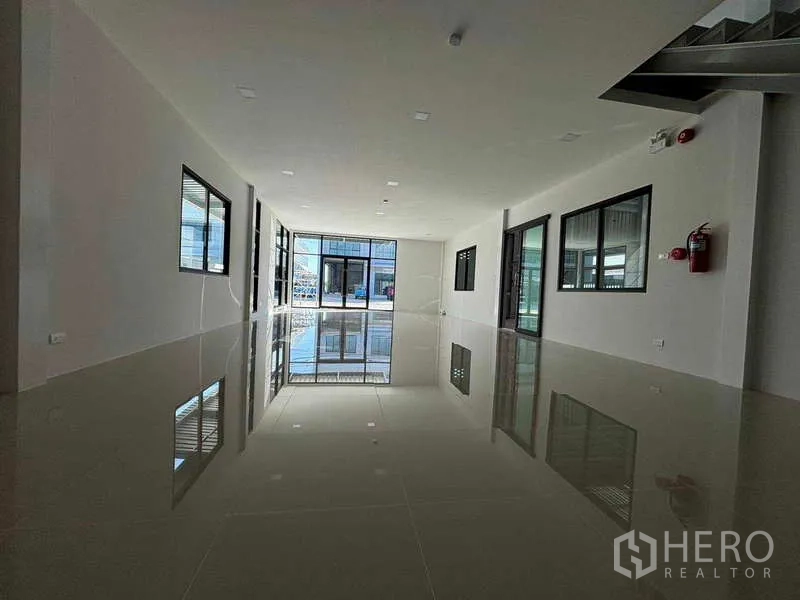 Factory for rent in Bang Bo, Samut Prakan - Long upper‑floor office space with windows on both sides and visible fire extinguishers.