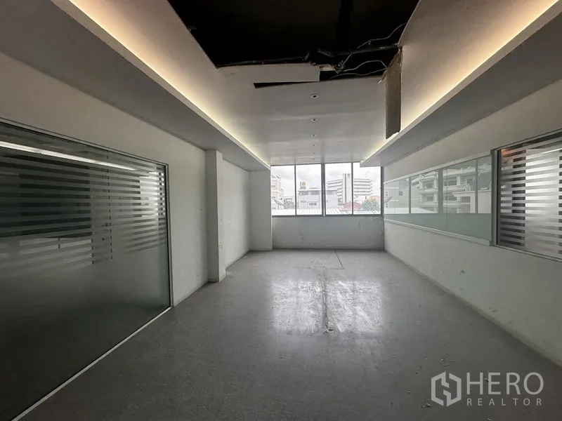 Office Space for rent in Khlong Toei, Bangkok - Narrow office with cove lighting, frosted glass and a city-view window.